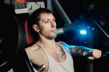 Göğüs kasları bir simülatör spor salonunda yakışıklı atletik erkek trenler.