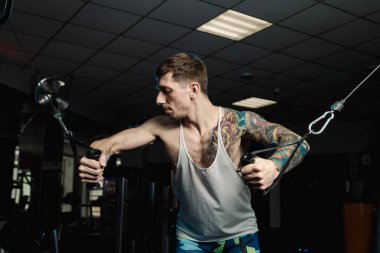 Göğüs kasları bir blok simülatör spor salonunda yakışıklı atletik erkek trenler.