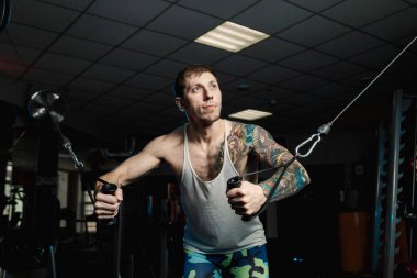 Göğüs kasları bir blok simülatör spor salonunda yakışıklı atletik erkek trenler.