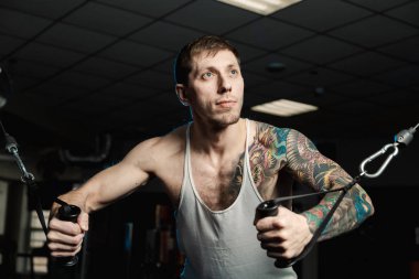 Göğüs kasları bir blok simülatör spor salonunda yakışıklı atletik erkek trenler.