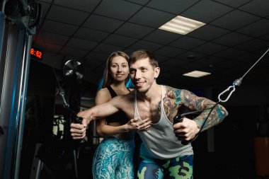 Aktif güzel fitness modeli kız sporcu spor salonunda bir blok simülatör trenler.