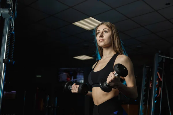 Young and beautiful woman working out with dumbbells in gym. Biceps curls. — Stock Photo, Image