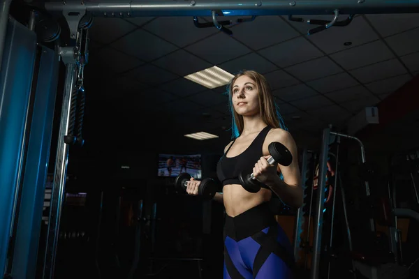 Mujer joven y hermosa haciendo ejercicio con pesas en el gimnasio. Bíceps rizos . — Foto de Stock