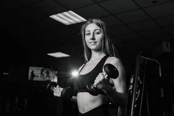 Mujer joven y hermosa haciendo ejercicio con pesas en el gimnasio. Bíceps rizos . —  Fotos de Stock