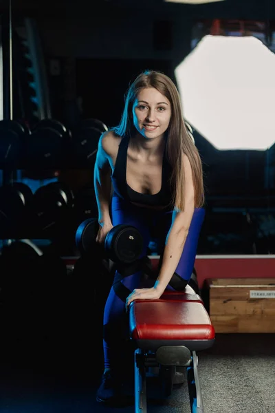 Боковой вид красивой фитнес-женщины тренировки с гирями над скамейкой упражнений в тренажерном зале . — стоковое фото