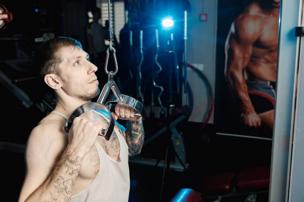 Hombre atlético guapo haciendo ejercicio en la máquina de gimnasio en el gimnasio . —  Fotos de Stock