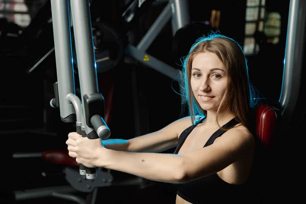 Aktiv smuk fitness model pige træner brystfinner muskler på en simulator i gymnastiksalen . - Stock-foto