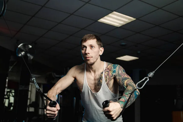 Hombre atlético guapo entrena los músculos pectorales en un simulador de bloque en el gimnasio . —  Fotos de Stock