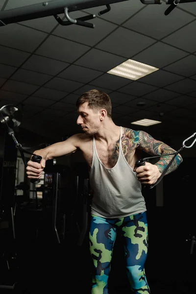 Przystojny mężczyzna sportowiec trenuje mięśni piersiowych na symulatorze bloku w siłowni. — Zdjęcie stockowe