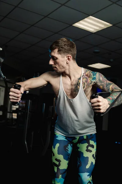 Przystojny mężczyzna sportowiec trenuje mięśni piersiowych na symulatorze bloku w siłowni. — Zdjęcie stockowe