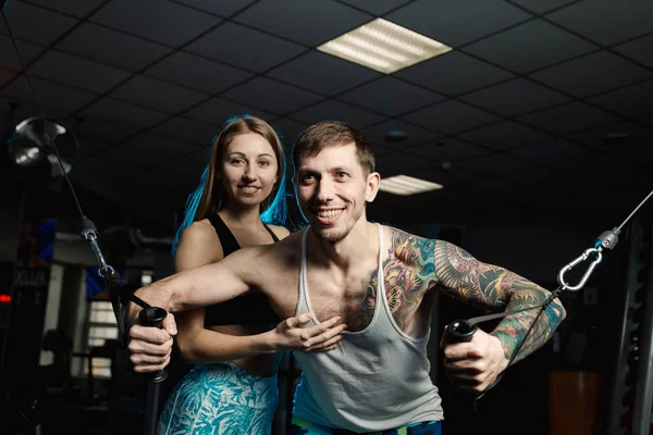 Aktif güzel fitness modeli kız sporcu spor salonunda bir blok simülatör trenler.