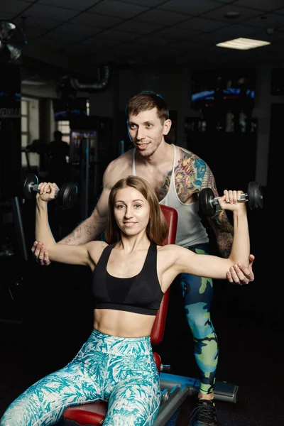 Aktif güzel fitness modeli kız ve spor salonunda bankta dumbbells ile eğitim onu antrenman ör.