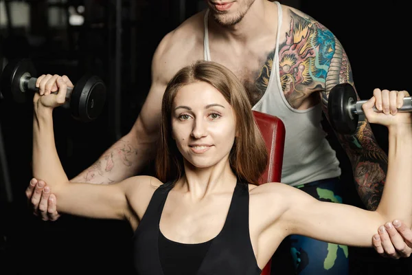 Aktif güzel fitness modeli kız ve spor salonunda bankta dumbbells ile eğitim onu antrenman ör.