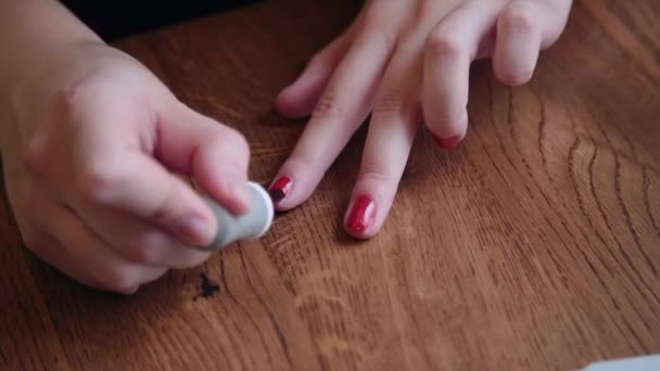 Eine schöne Geschäftsfrau sitzt an einem Tisch mit einem Laptop in einem Café und lackiert ihre Nägel. — Stockvideo