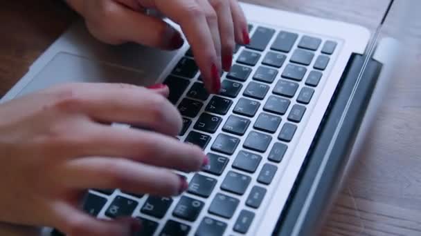 Una hermosa mujer de negocios está sentada en una mesa con un portátil en un café y trabajando . — Vídeo de stock