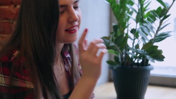 Uma bela mulher de negócios está sentada a uma mesa com um laptop em um café e trabalhando . — Vídeo de Stock