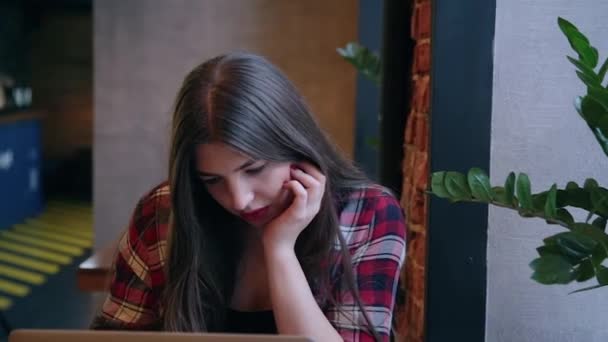 Güzel bir iş kadını bir kafe ve çalışma bir dizüstü bilgisayar ile bir masada oturuyor. — Stok video