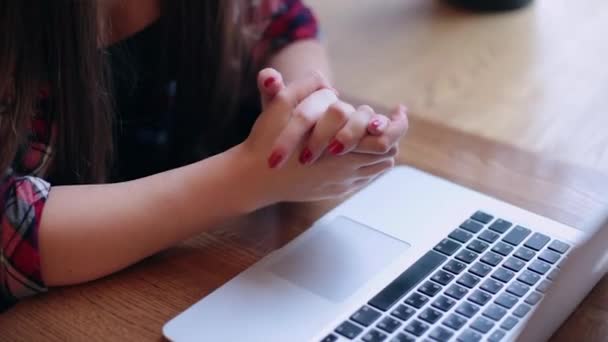 Una bella donna d'affari è seduta a un tavolo con un computer portatile in un caffè e di lavoro . — Video Stock