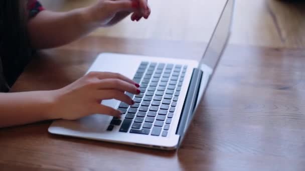 Uma bela mulher de negócios está sentada a uma mesa com um laptop em um café e trabalhando . — Vídeo de Stock