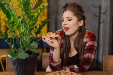 Bir kafede bir pizza ile bir masada oturan güzel ve seksi kız.