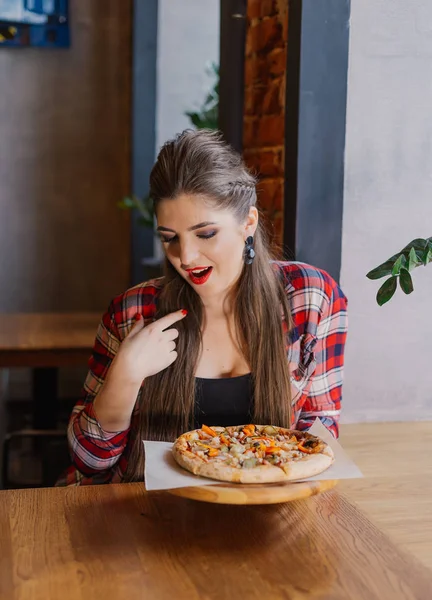 Mooi en sexy meisje bij het raam in een café zitten en houden van een pizza. — Stockfoto