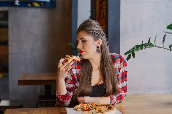 Красивая и сексуальная девушка сидит у окна в кафе и ест пиццу . — стоковое фото