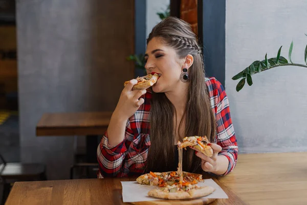 Красивая и сексуальная девушка сидит у окна в кафе и ест пиццу . — стоковое фото