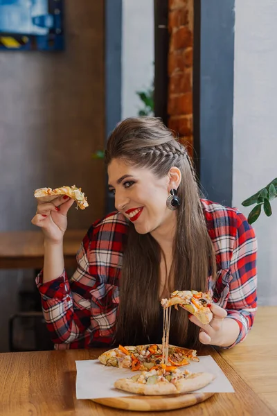 Menina bonita e sexy sentada à janela em um café e comer pizza . — Fotografia de Stock