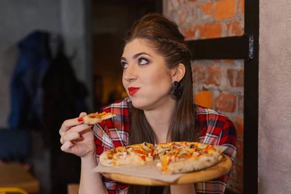 Menina bonita e sexy sentada à janela em um café e comer pizza . — Fotografia de Stock