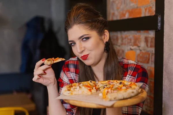 Menina bonita e sexy sentada à janela em um café e comer pizza . — Fotografia de Stock