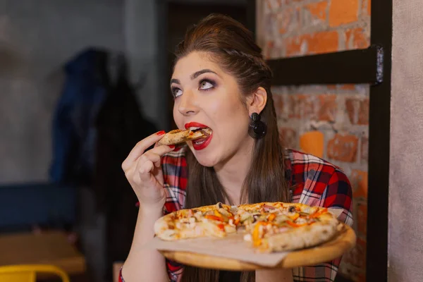 Mooi en sexy meisje bij het raam in een café zitten en eten van pizza. — Stockfoto