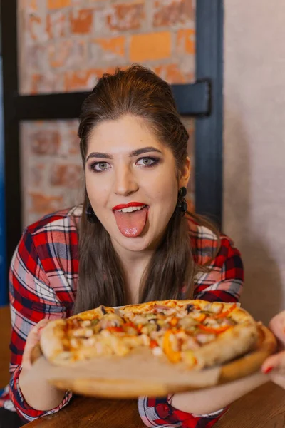 Mooi en sexy meisje bij het raam in een café zitten en eten van pizza. — Stockfoto