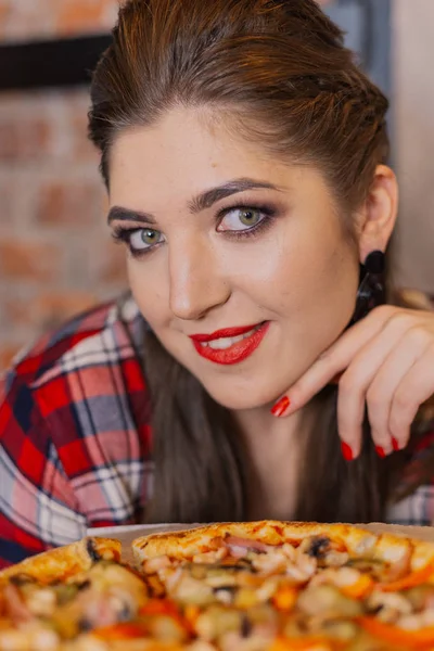 Mooi en sexy meisje bij het raam in een café zitten en eten van pizza. — Stockfoto