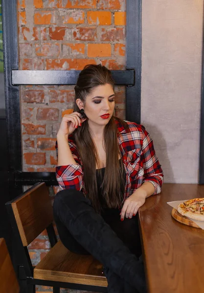 Menina bonita e sexy sentado em uma mesa com uma pizza em um café . — Fotografia de Stock