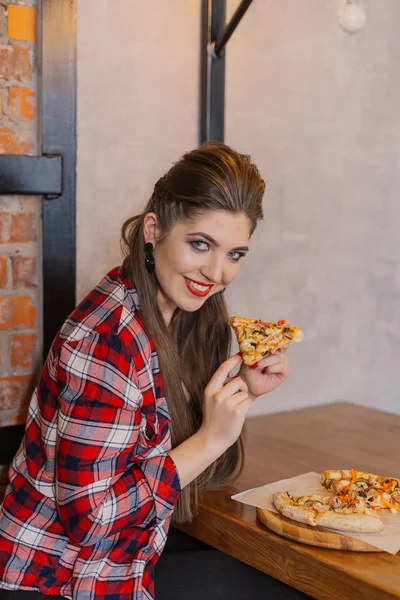 Menina bonita e sexy sentado em uma mesa com uma pizza em um café . — Fotografia de Stock