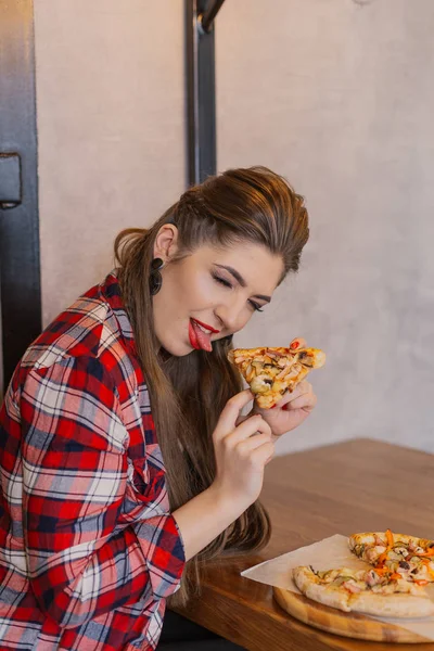 Mooi en sexy meisje zitten aan een tafel met een pizza in een café. — Stockfoto