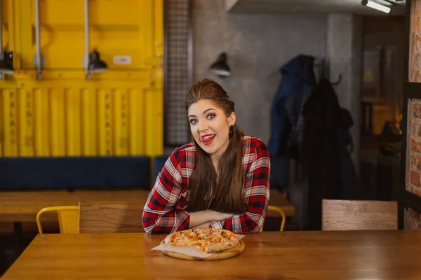 Красивая и сексуальная девушка сидит за столом с пиццей в кафе . — стоковое фото