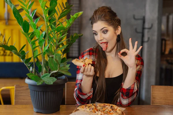 Mooi en sexy meisje zitten aan een tafel met een pizza in een café. — Stockfoto