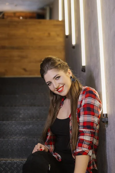 Belle et sexy fille posant pour un photographe sur les escaliers en fer noir avec des lampes dans un café . — Photo