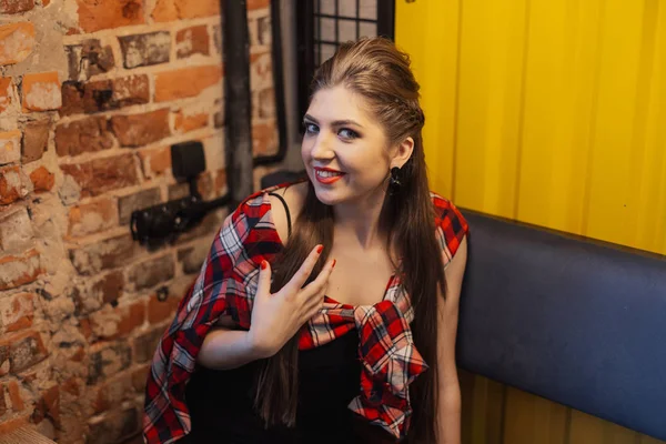 Beautiful and sexy girl sitting by the window in a cafe and smiling. — Stock Photo, Image