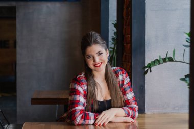 Bir kafede cam kenarında oturan ve gülümseyen güzel ve seksi kız.