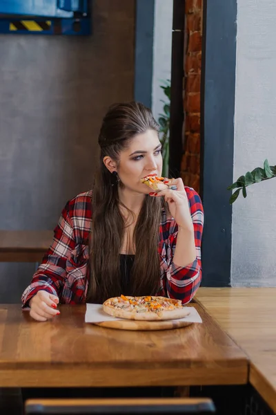 Mooi en sexy meisje zitten aan een tafel met een pizza in een café. — Stockfoto