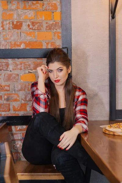 Menina bonita e sexy sentado em uma mesa com uma pizza em um café . — Fotografia de Stock