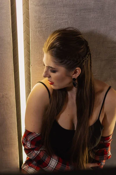 Natural light indoor portrait of young pretty girl with long dark brown hair, natural makeup and red lips. Stylish woman looking at you.