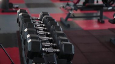 Eğitim için spor salonunda dumbbells rafları üzerinden alarak yakışıklı atletik erkek