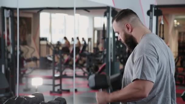 Guapo atlético hombre entrenamiento dumbbell bíceps en el gimnasio . — Vídeos de Stock