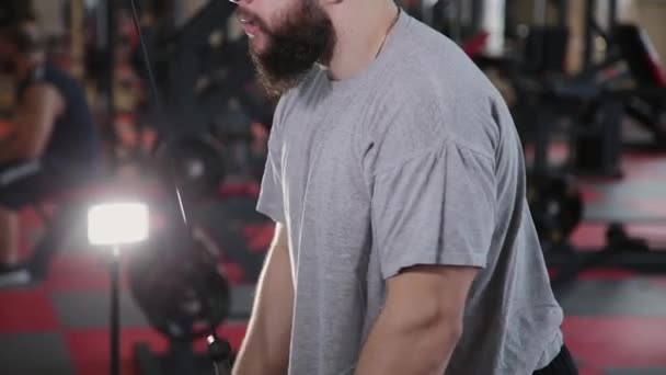 Bel homme athlétique entraîne triceps sur le simulateur de bloc dans la salle de gym . — Video