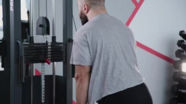 Triceps blok simülatör spor salonunda yakışıklı atletik erkek trenler.