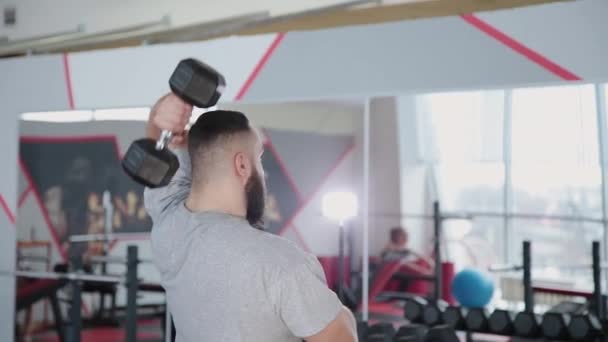 Hombre atlético guapo entrena tríceps en el simulador de bloque en el gimnasio . — Vídeo de stock