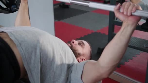 Handsome athletic man performs bench press on the bench in the gym. — Stock Video